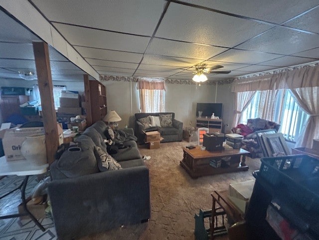 carpeted living room featuring ceiling fan and a drop ceiling