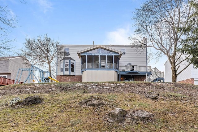 rear view of property featuring a sunroom and a playground