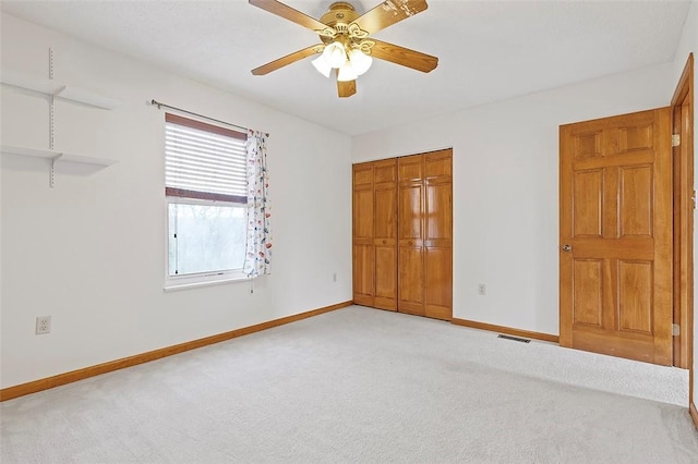 unfurnished bedroom featuring light colored carpet, a closet, and ceiling fan