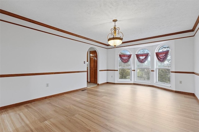 empty room featuring light hardwood / wood-style flooring, a textured ceiling, and ornamental molding