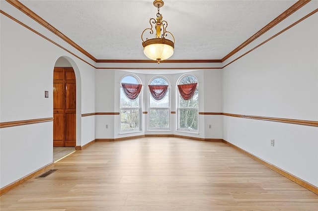 spare room with light hardwood / wood-style floors, ornamental molding, and a textured ceiling