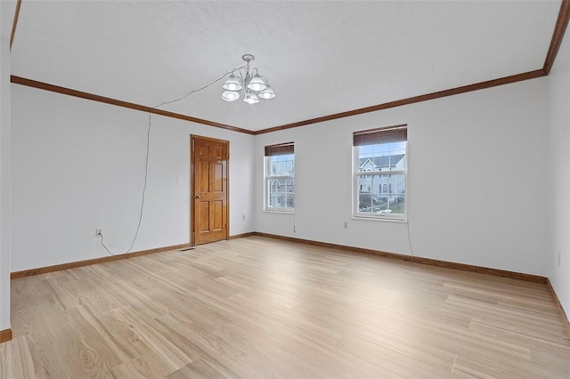 empty room featuring crown molding, a chandelier, and light hardwood / wood-style floors