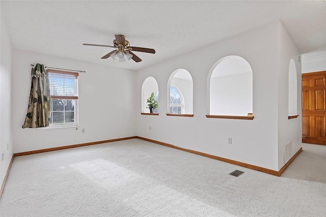 carpeted spare room featuring ceiling fan and a wealth of natural light