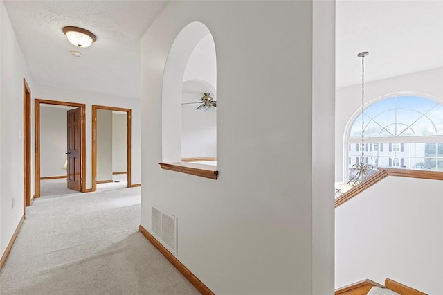 hall featuring a textured ceiling and light carpet