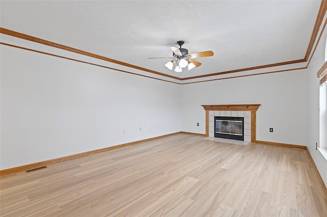 unfurnished living room with a tiled fireplace, ceiling fan, light hardwood / wood-style floors, and ornamental molding