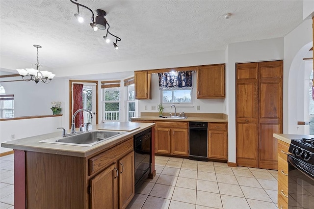 kitchen with sink, black appliances, decorative light fixtures, a center island with sink, and an inviting chandelier