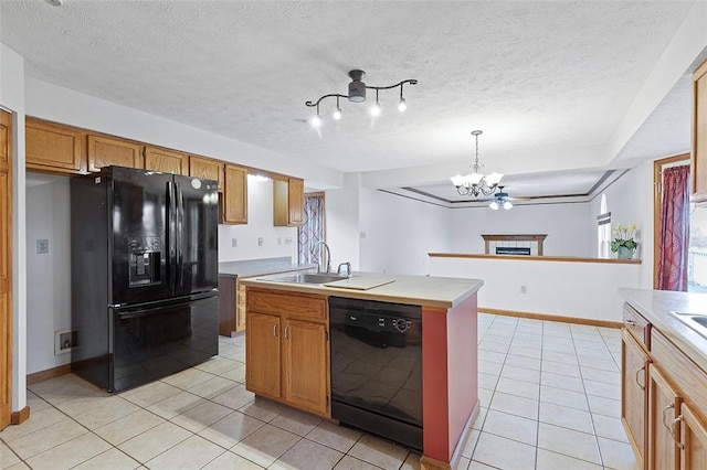 kitchen featuring black appliances, sink, hanging light fixtures, an island with sink, and a notable chandelier