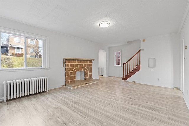 unfurnished living room featuring radiator, a fireplace, and light hardwood / wood-style flooring