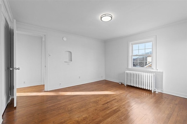 spare room featuring hardwood / wood-style floors, radiator, and crown molding