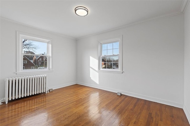 unfurnished room featuring hardwood / wood-style flooring, a wealth of natural light, ornamental molding, and radiator