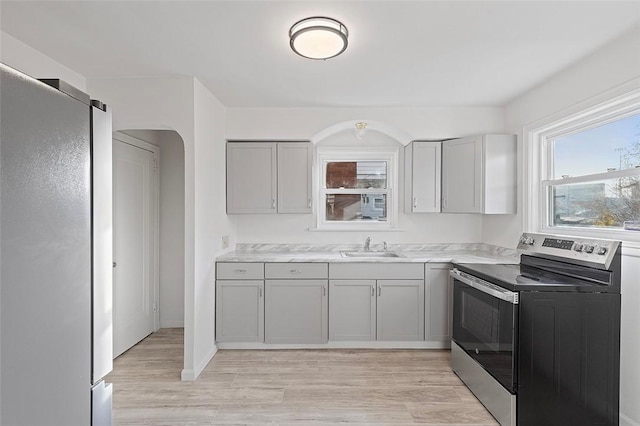 kitchen featuring gray cabinetry, sink, appliances with stainless steel finishes, and light hardwood / wood-style flooring