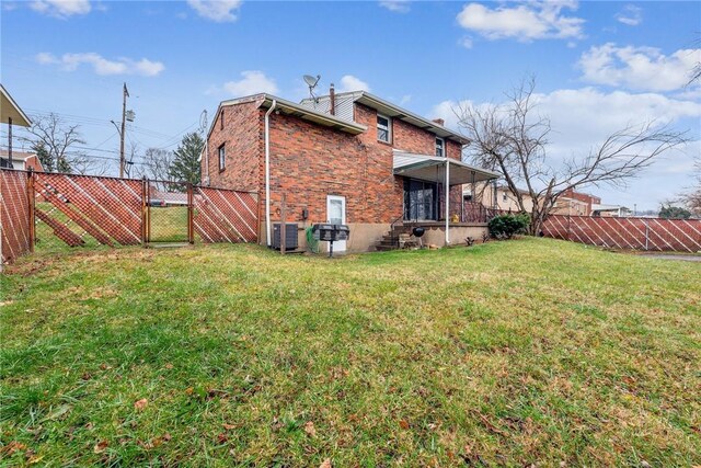 rear view of property featuring a yard and central air condition unit