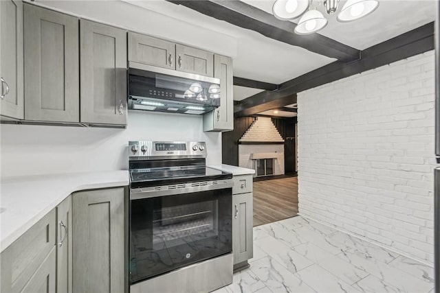 kitchen with stainless steel appliances, gray cabinetry, and brick wall