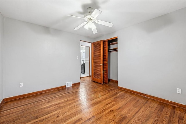 unfurnished bedroom featuring hardwood / wood-style floors, ceiling fan, and a closet