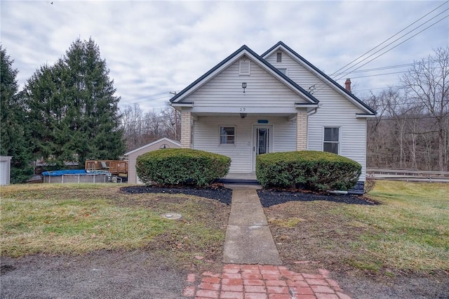 bungalow featuring covered porch and a front yard