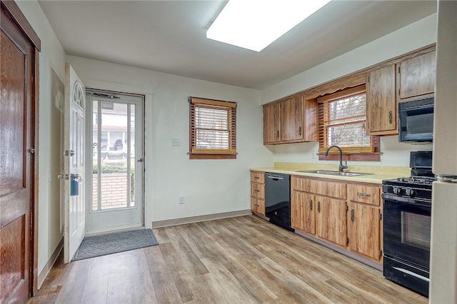 kitchen featuring sink, black appliances, and light hardwood / wood-style flooring