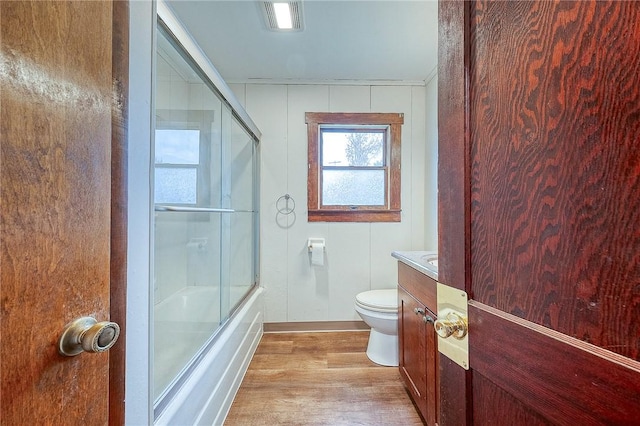 full bathroom with hardwood / wood-style flooring, vanity, toilet, and shower / bath combination with glass door