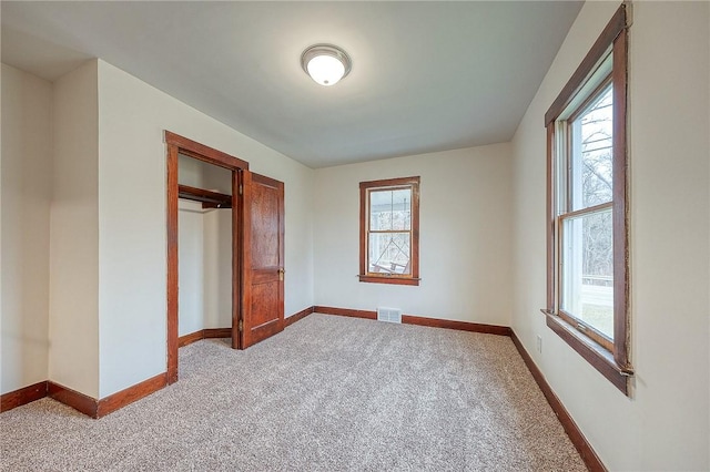 unfurnished bedroom featuring multiple windows, a closet, and light colored carpet