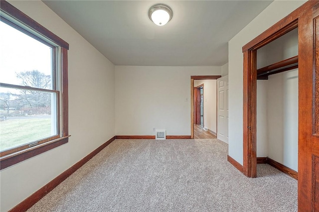 unfurnished bedroom featuring light colored carpet and a closet