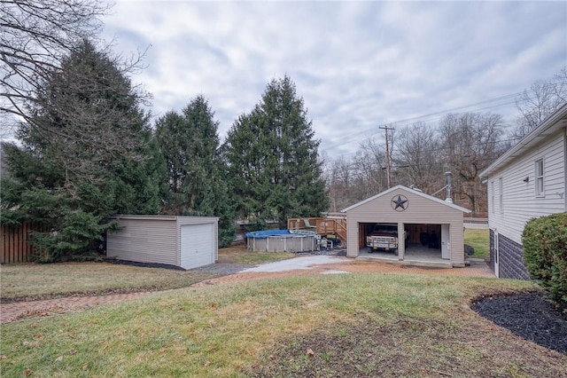 view of yard featuring an outbuilding, a covered pool, and a garage