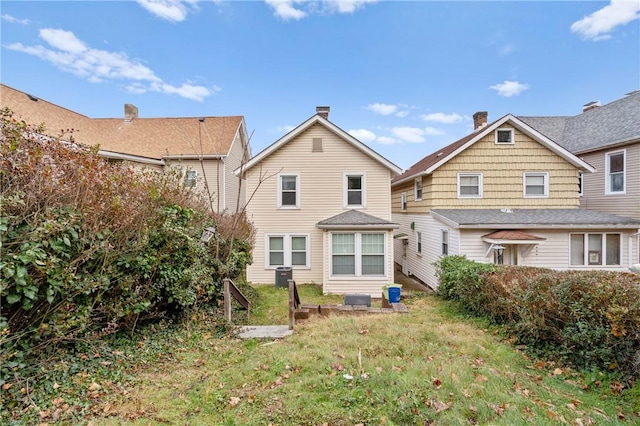 back of property with a yard and central AC