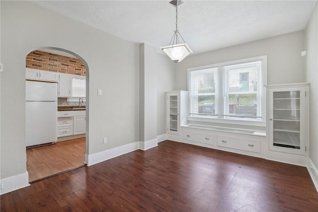 spare room featuring brick wall, a textured ceiling, dark wood-type flooring, and sink