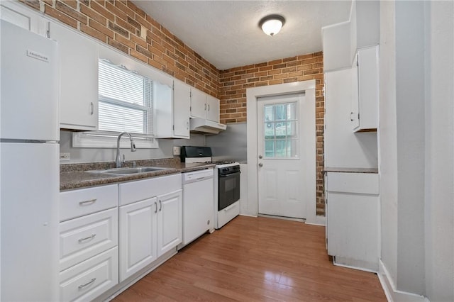 kitchen with white appliances, white cabinets, sink, light hardwood / wood-style flooring, and brick wall