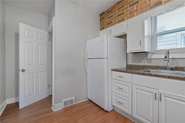 kitchen featuring brick wall, sink, light hardwood / wood-style flooring, white fridge, and white cabinetry