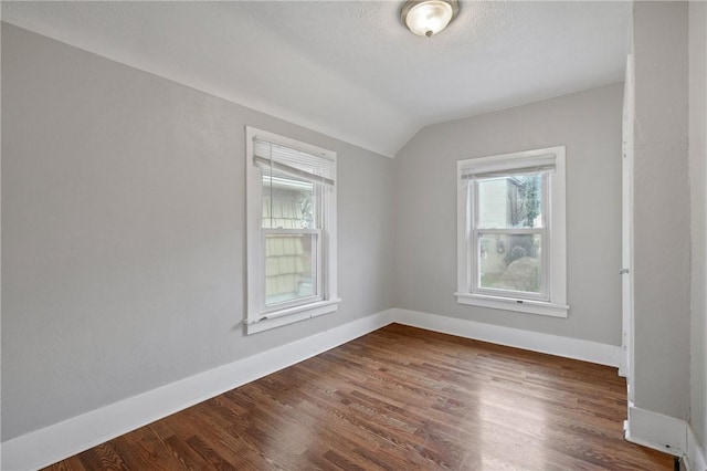 empty room with dark hardwood / wood-style floors and lofted ceiling