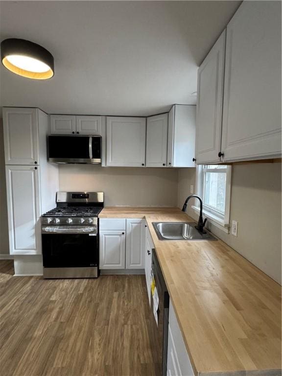 kitchen featuring appliances with stainless steel finishes, butcher block counters, and white cabinets