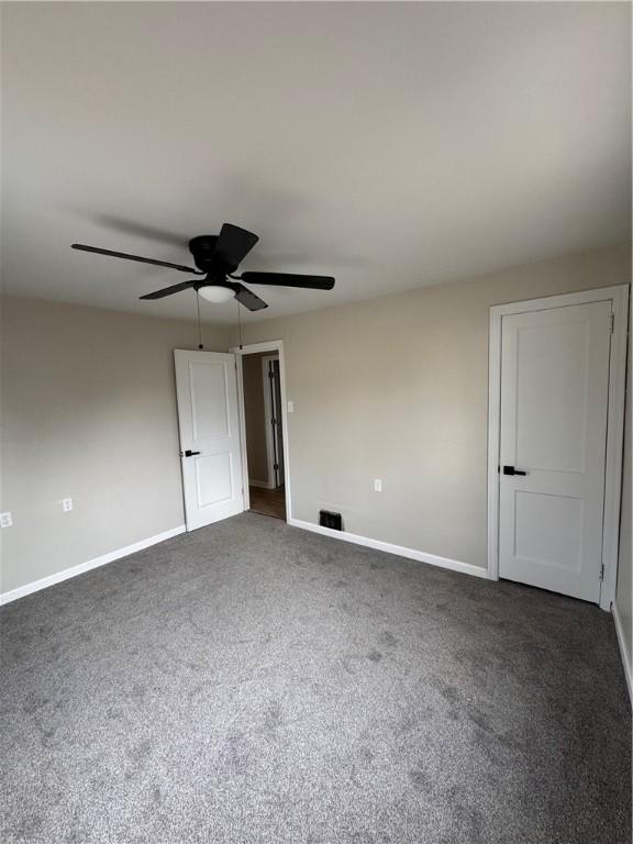 unfurnished bedroom featuring dark carpet and ceiling fan