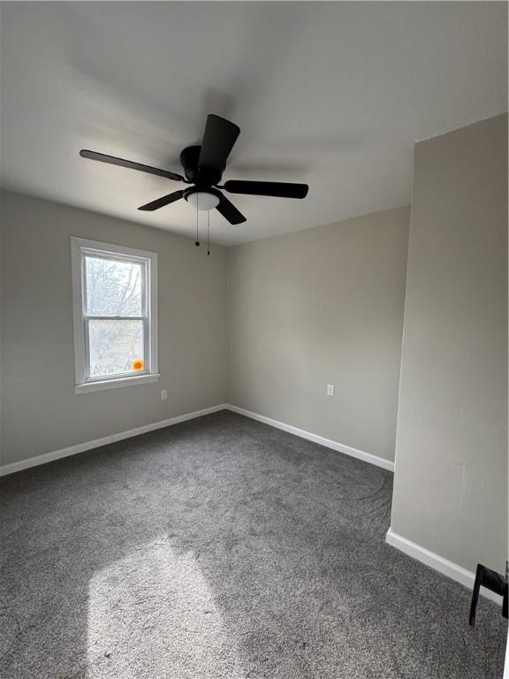 unfurnished room with ceiling fan and dark carpet