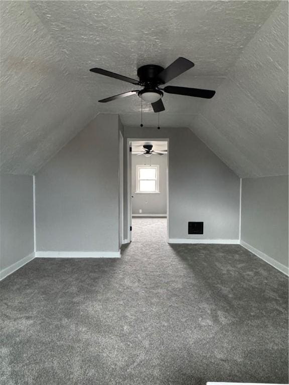 bonus room featuring vaulted ceiling, a textured ceiling, and dark colored carpet