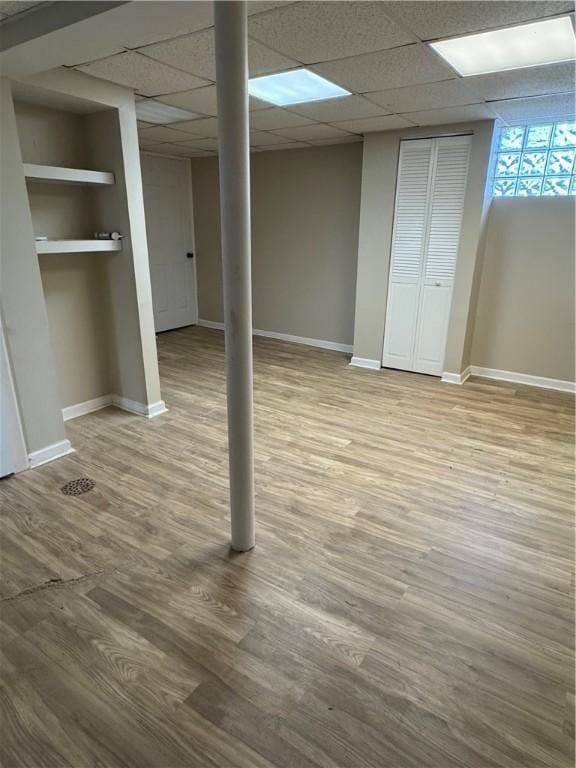 basement featuring a drop ceiling and wood-type flooring