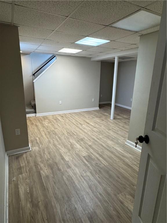 basement featuring a drop ceiling and hardwood / wood-style flooring