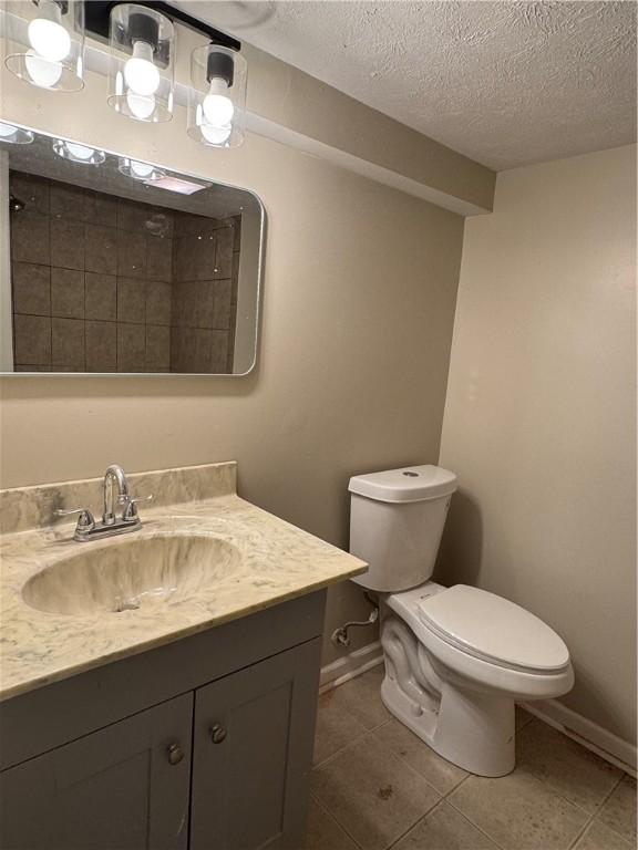 bathroom with tile patterned floors, vanity, toilet, and a textured ceiling