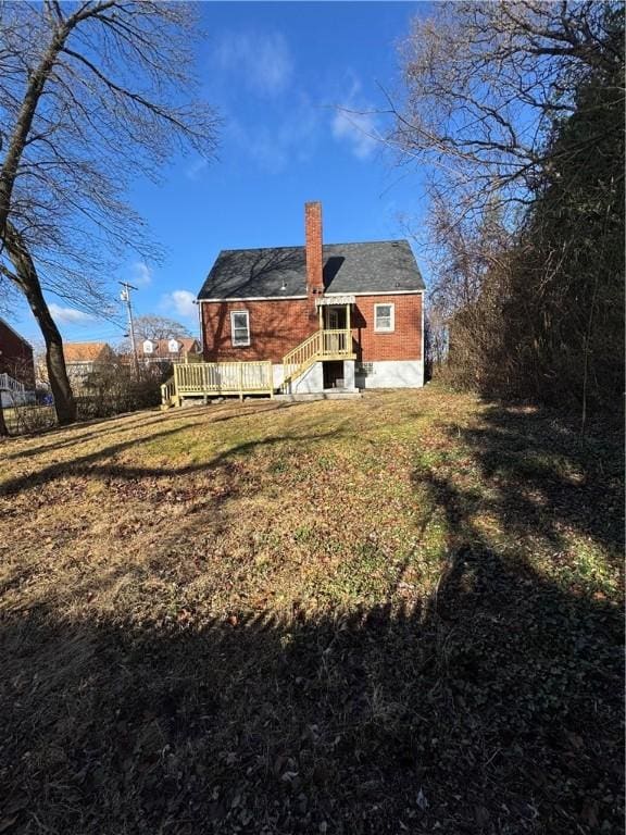 back of property featuring a wooden deck and a yard