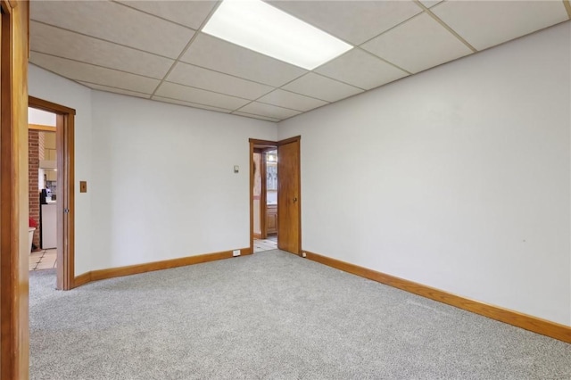 spare room with a paneled ceiling and light colored carpet