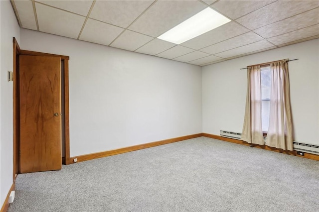 spare room with a drop ceiling, carpet floors, and a baseboard heating unit