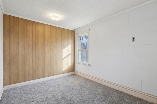 unfurnished room with crown molding, wooden walls, and carpet floors