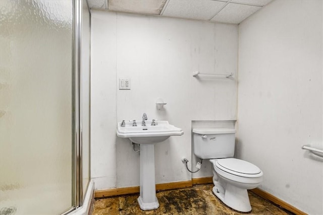 bathroom featuring toilet, a drop ceiling, a shower with shower door, and sink