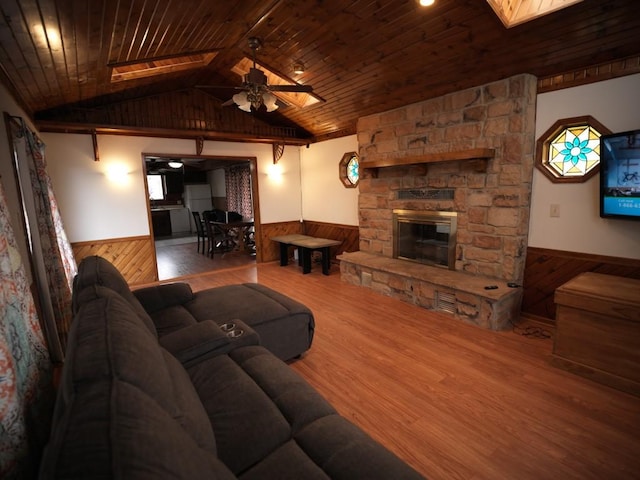 living room featuring a stone fireplace, ceiling fan, lofted ceiling, and wood ceiling