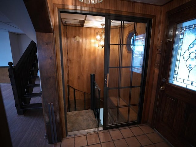 tiled entryway with a chandelier and wood walls