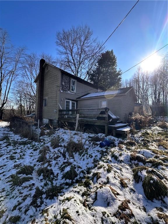 snow covered back of property with a deck