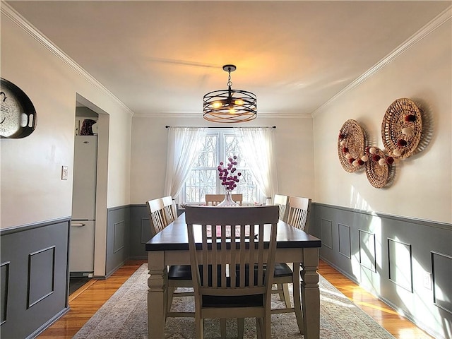 dining space with light hardwood / wood-style flooring, crown molding, and an inviting chandelier