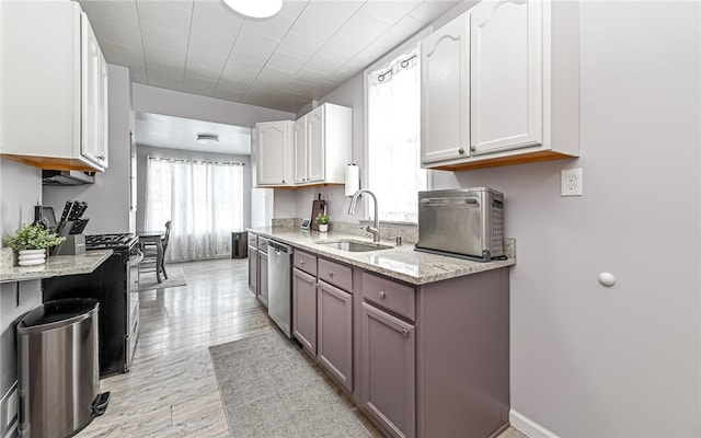 kitchen featuring white cabinets, sink, light hardwood / wood-style flooring, appliances with stainless steel finishes, and light stone counters