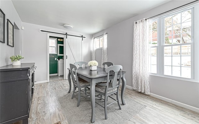 dining space featuring a barn door and light hardwood / wood-style floors