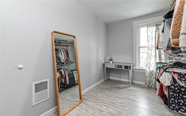 walk in closet with light hardwood / wood-style flooring