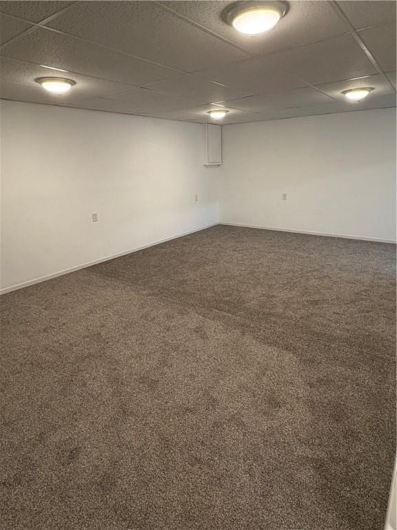 basement featuring a paneled ceiling and dark carpet