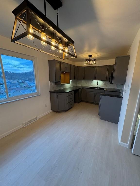 kitchen featuring sink, hanging light fixtures, decorative backsplash, light wood-type flooring, and range